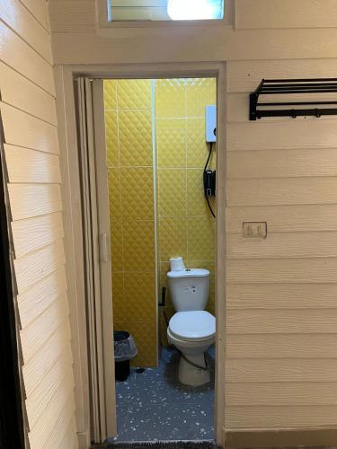a bathroom with a toilet and a yellow wall at La Locanda in Bangkok