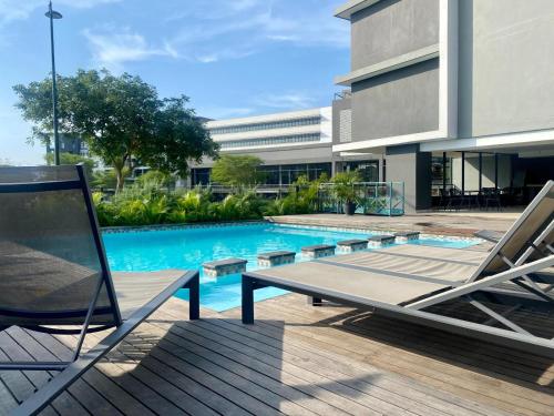 una piscina con 2 tumbonas junto a un edificio en The Sapphire Light - Studio Apartment, en Durban
