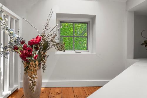 a vase with flowers in a room with a window at Sunny Westport Studio Apt. Above Historic Mill in Westport