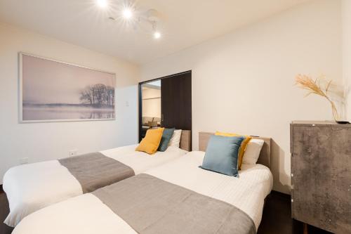 two beds in a room with white walls at ホテル富士見マンション in Tokyo
