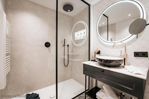 a bathroom with a shower and a sink and a mirror at Strandhotel Kurhaus Juist in Juist