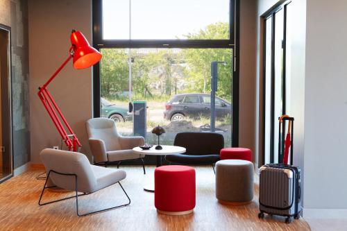 a room with chairs and a table and a lamp at ibis budget Hotel Berlin Airport in Berlin