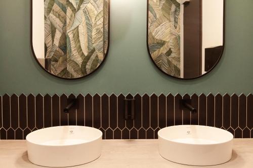 two sinks in a bathroom with two mirrors at ibis budget Hotel Berlin Airport in Berlin