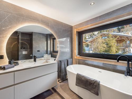 La salle de bains est pourvue de 2 lavabos, d'une baignoire et d'une fenêtre. dans l'établissement Charmant appartement au centre avec sauna et balcon à Megève - FR-1-569-114, à Megève