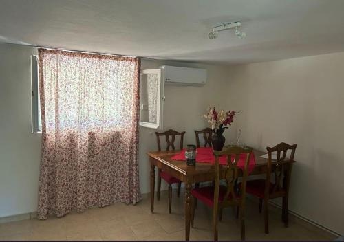 Un comedor con mesa y sillas y una ventana. en Tiny Comfort House, en Kyllini