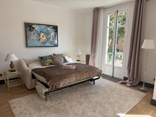 Un dormitorio con una cama y una ventana grande. en Magnifique studio entier avec terrasse Saint Jean Cap Ferrat, en Saint-Jean-Cap-Ferrat