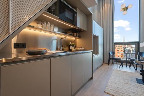 a kitchen with white cabinets and a large window at Unity Helsinki - A Studio Hotel in Helsinki