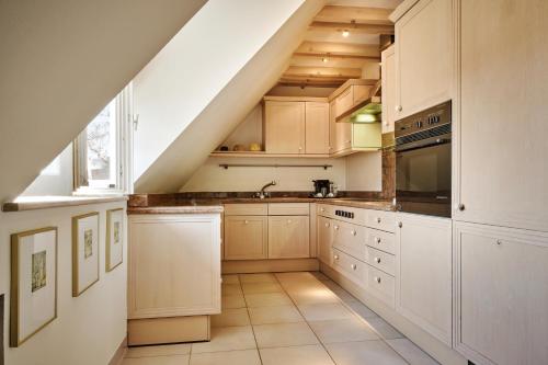 an attic kitchen with white cabinets and a staircase at Hotel & Spa A la cour d'Alsace by HappyCulture in Obernai