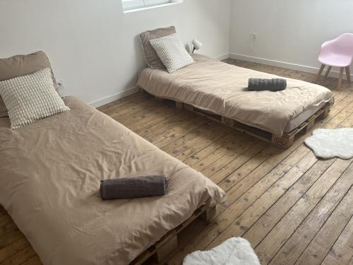 1 dormitorio con 2 camas y silla rosa en Ferme Cosy et Paisible au Bord de l'Eure, en Criquebeuf-sur-Seine