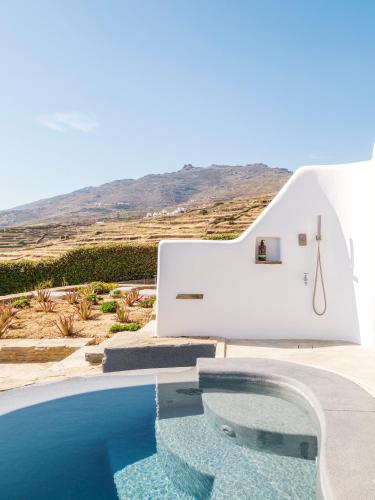 a swimming pool next to a white house with a hill in the background at Tinostra Casa in Agios Romanos