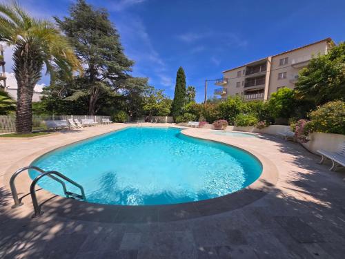 une grande piscine dans une cour avec des arbres et un bâtiment dans l'établissement Appartement mer et centre ville, à Sainte-Maxime