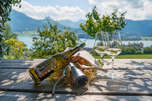 a bottle of wine and glasses on a wooden table at Altroiterhof in St. Wolfgang