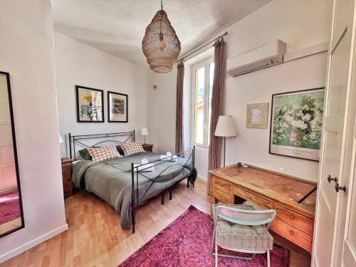 une chambre avec un lit, un bureau et une fenêtre dans l'établissement Lumineux et charmant deux pièce - Menton, à Menton