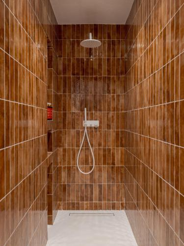 a brown tiled bathroom with a shower with a hose at Aegean Colors Paros in Naousa