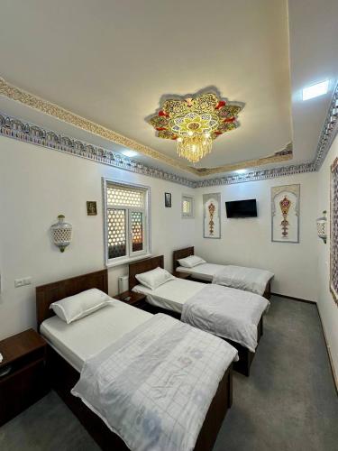 a room with three beds and a chandelier at Shom Hotel with Terraca in Bukhara