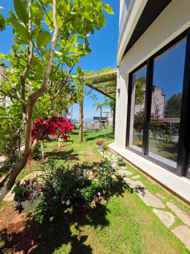 a garden outside a house with a tree and flowers at Valza Boutique Hotel in Vlorë