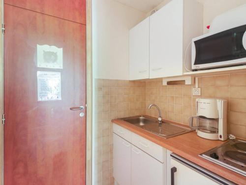une cuisine avec des placards blancs et une porte rouge dans l'établissement Studio cosy 4 pers, balcon sud, pied des pistes - La Mongie - FR-1-404-124, à La Mongie