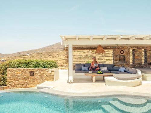 a woman sitting on a couch next to a pool at Tinostra Casa in Agios Romanos