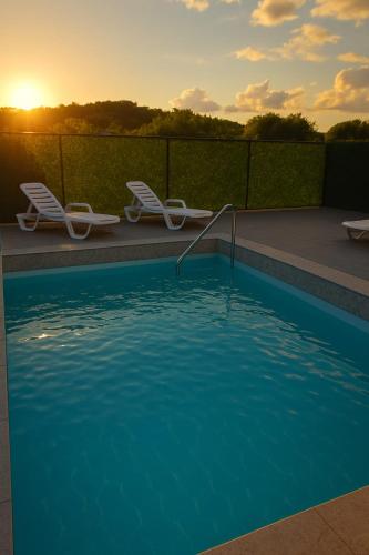 a swimming pool with two lounge chairs and the sunset at Z House kuća za odmor in Blagaj