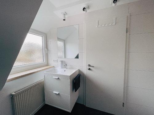 a white bathroom with a sink and a mirror at Your Home Base - Vacation & Work close to Munich in Dachau
