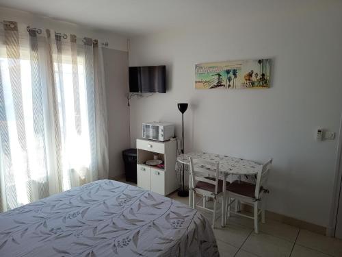 - une chambre avec un lit, une table et un four micro-ondes dans l'établissement Chambre privée climatisée chez particulier, WIFI, à Perpignan