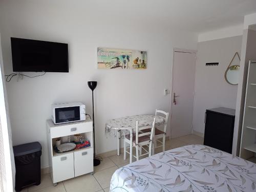 une chambre avec un lit, une table et une télévision dans l'établissement Chambre privée climatisée chez particulier, WIFI, à Perpignan