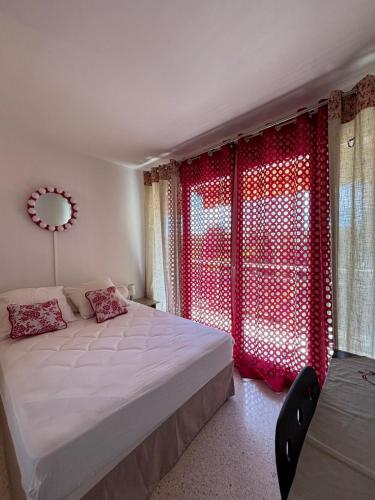 une chambre avec un lit et une fenêtre avec des rideaux rouges dans l'établissement Aix en Provence, dans grande résidence arborée, appartement de 80m2, à Aix-en-Provence