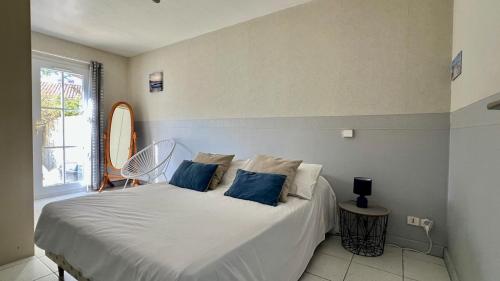 une chambre avec un lit blanc avec des oreillers bleus dans l'établissement 100 L'Orneau - Plain-pied avec terrasse, idéalement situé, à Saint-Martin-de-Ré