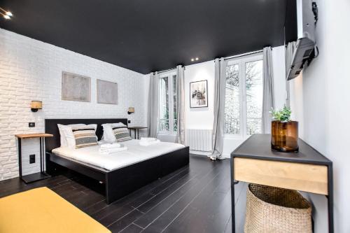 - une chambre noire et blanche avec un lit et un bureau dans l'établissement Duplex agréable Paris 20ᵉ - Belleville, à Paris