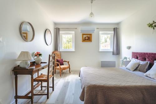 a bedroom with a bed and a desk and a chair at Gite des Tropiques in Genouillé