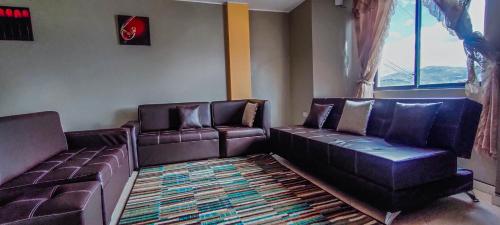 a waiting room with two leather couches and a rug at Departamento en conjunto residencial in Riobamba