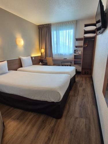 a hotel room with two beds and a desk at CAMPANILE PARIS 12 - Bercy Village in Paris