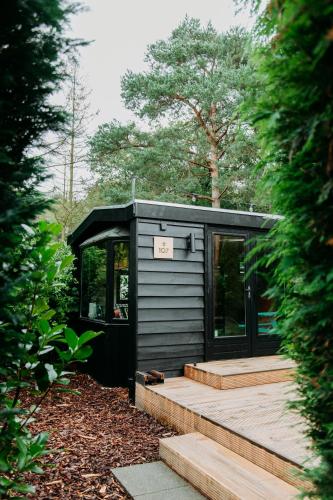 a black tiny house sitting on a wooden deck at Bumblebee Cabin in Diessen