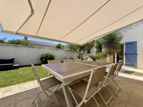 une table et des chaises en bois sous un grand parasol dans l'établissement Maison neuve 8 pers. avec terrasse, 600m de la plage, La Cotinière, Saint-Pierre-d'Oléron - FR-1-246A-185, à Saint-Pierre-dʼOléron