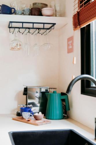 a kitchen counter with a sink and glasses on a shelf at Bumblebee Cabin in Diessen