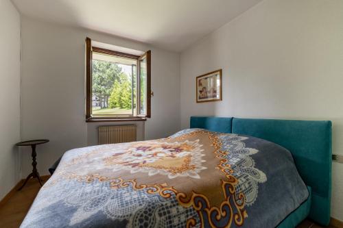 Un dormitorio con una cama azul y una ventana. en Casa Lugli by go new location, en Cavalese