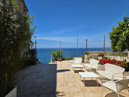 a patio with white chairs and the ocean in the background at Oasi Relais in Vico Equense