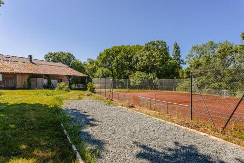 a tennis court in front of a house at Gite du Parc in Genouillé
