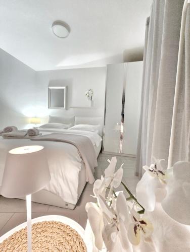 a white bedroom with a large bed and white flowers at SeaHouse by Jelena in Bibinje