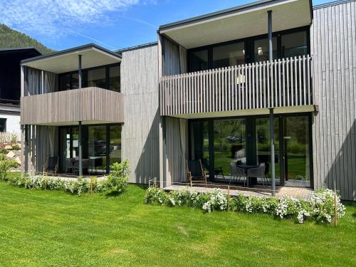a house with glass windows and a lawn at Bio Design Appartements DAS GRAUE SCHAF - Kärnten Card im Sommer inklusive in Bad Kleinkirchheim
