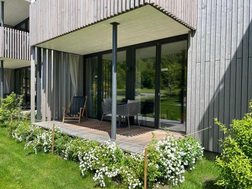 a glass house with a patio and flowers at Bio Design Appartements DAS GRAUE SCHAF - Kärnten Card im Sommer inklusive in Bad Kleinkirchheim