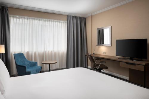 a hotel room with a bed and a desk and a television at Hilton Paris Charles De Gaulle Airport in Roissy-en-France