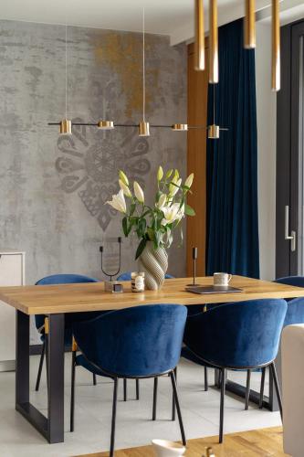 a dining room with a wooden table and blue chairs at Landscape Villas - LoftAffair Spa Collection in Kościelisko