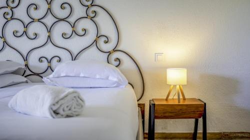 a bed with white pillows and a lamp on a table at Hotel La Tramontane in Saintes-Maries-de-la-Mer