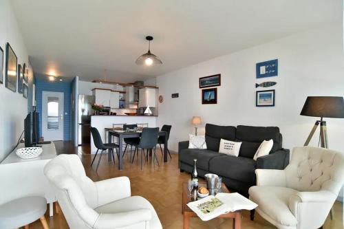 - un salon avec un canapé noir et des fauteuils blancs dans l'établissement Le grand jardin, à Saint-Malo