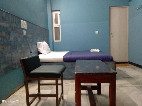 a room with a bed and a chair and a table at SM MANSION near Harbour & High court in Chennai
