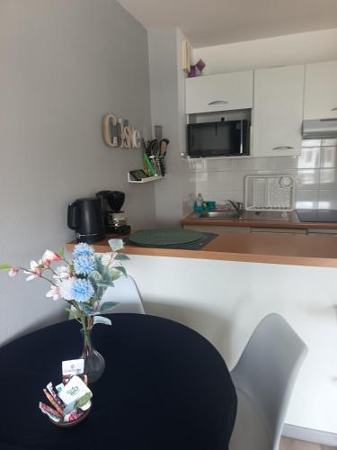 une cuisine avec un vase de fleurs sur une table dans l'établissement Appartement Ciboure golf et Nivel, à Ciboure