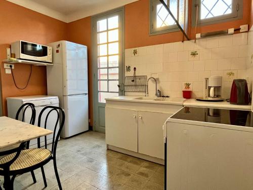 une cuisine avec un réfrigérateur blanc et une table dans l'établissement Maison 5 pièces 8 couchages ARGELES SUR MER AR000-070, à Argelès-sur-Mer