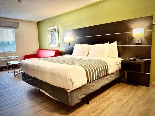 a hotel room with a large bed and a red chair at SureStay Plus Hotel by Best Western Kincardine in Kincardine