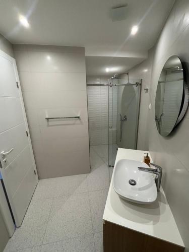 a white bathroom with a sink and a shower at Vuelo Sobre Bečići in Becici